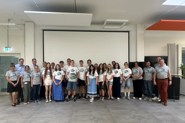 Group of students and teachers posing together in NETZSCH Science Cup T-shirts, celebrating creativity and teamwork in a modern event space.