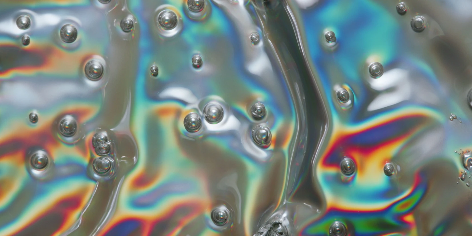 Smooth, glossy pink texture resembling a cosmetic cream, showcasing bubbles for an engaging visual on rheological properties.