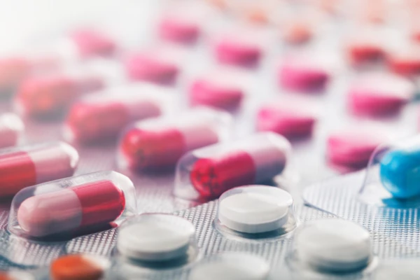 Capsule e compresse colorate disposte in un blister, che evidenziano le opzioni farmaceutiche per la salute e il benessere.