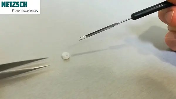 Próbka small paracetamolu jest ustawiana do pomiaru TGA przy użyciu specjalistycznych narzędzi w warunkach laboratoryjnych.