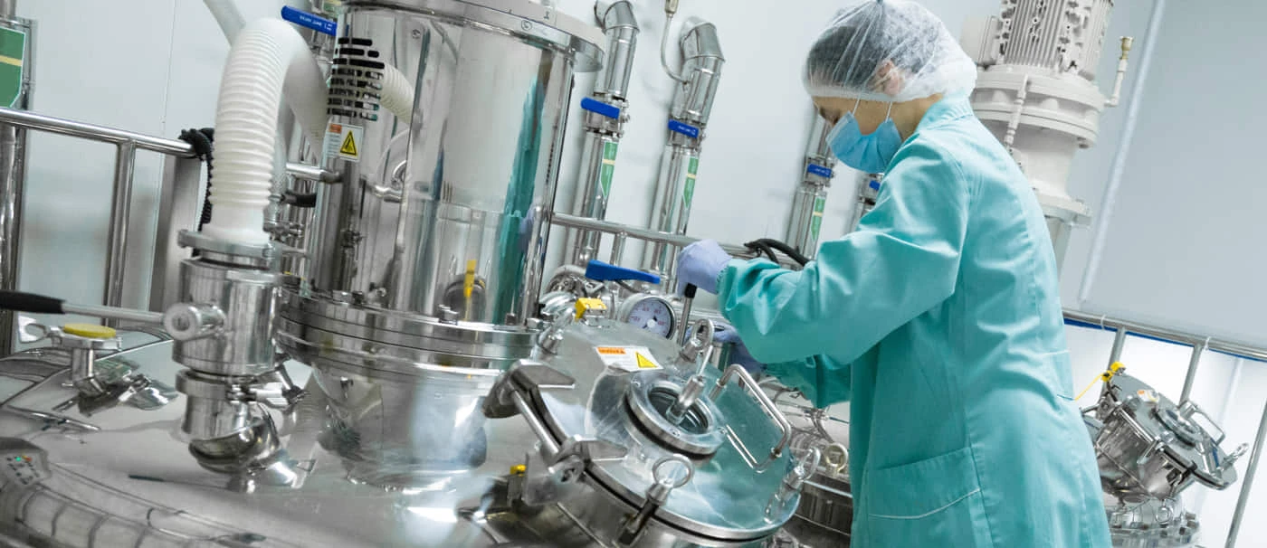 A technician in a blue lab coat and mask operates thermal conductivity testing equipment in a cleanroom environment.