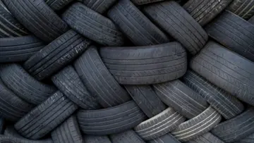 Un homme d'affaires portant des lunettes et une chemise à carreaux bleus, regardant l'objectif avec assurance sur un fond neutre.