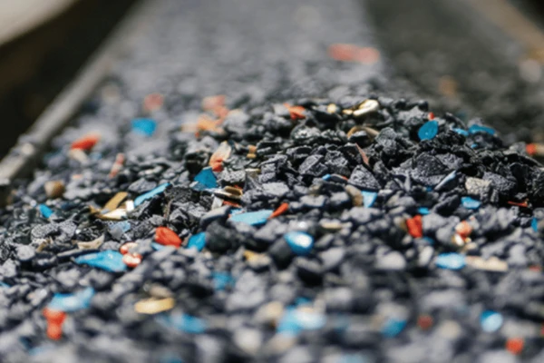 Granuli di gomma nera mescolati a frammenti colorati, utilizzati in applicazioni di analisi termica, che evidenziano le proprietà versatili del materiale.