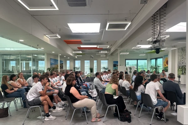 Students in white shirts attentively participate in a workshop at the NETZSCH Science Cup, with a modern, bright room setting.