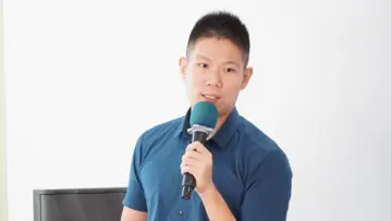 Professional man with glasses wearing a blue plaid shirt, looking confidently at the camera against a neutral background.